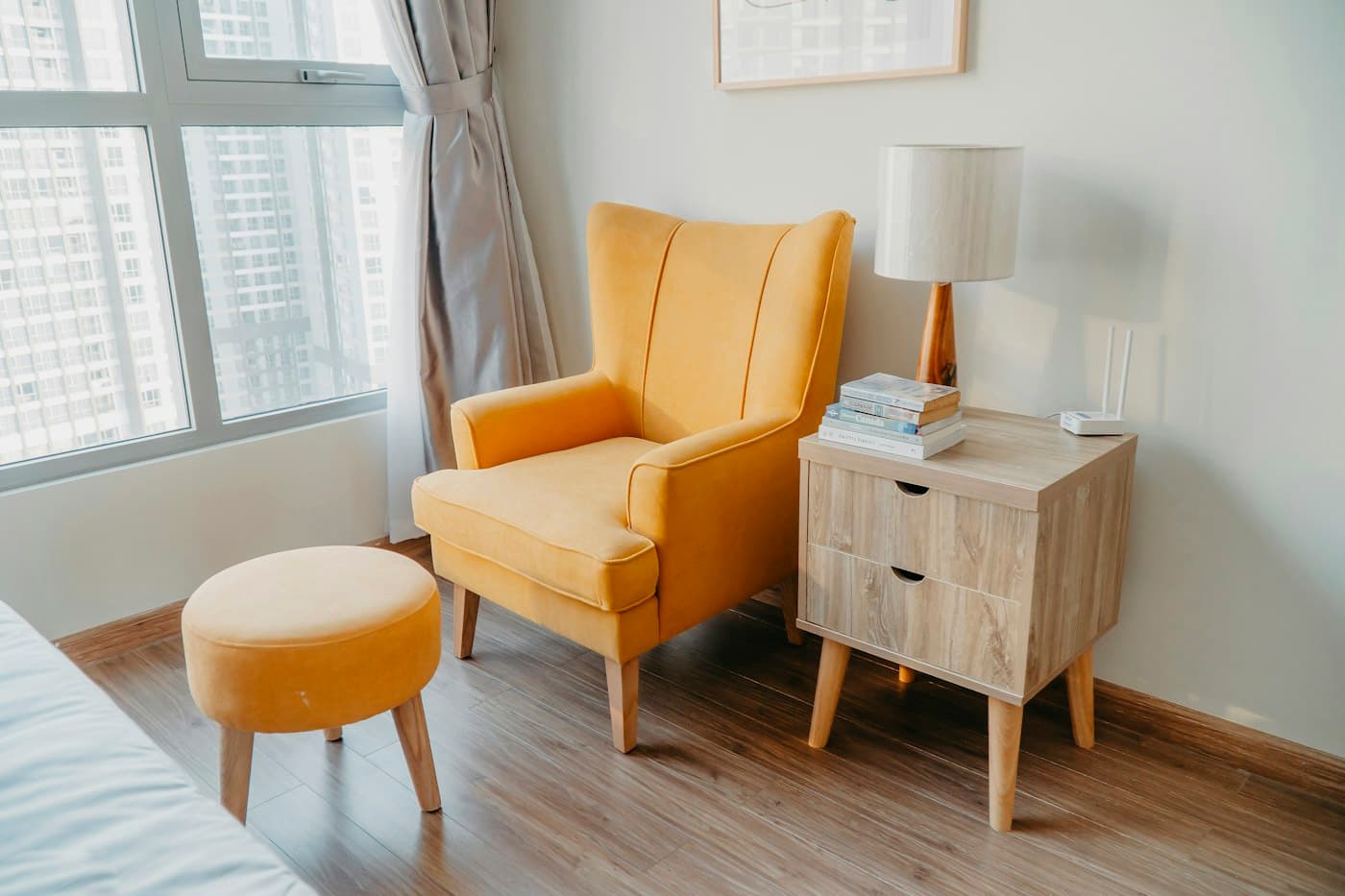 Mustard armchair and matching ottoman beside an oak nightstand