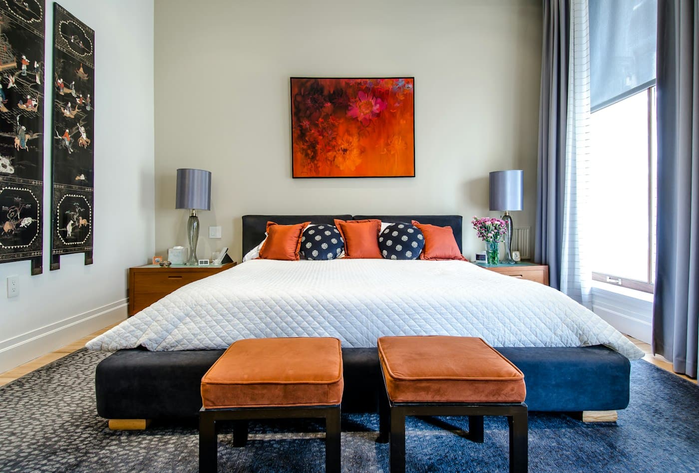 Bedroom with an upholstered bench and bold artwork