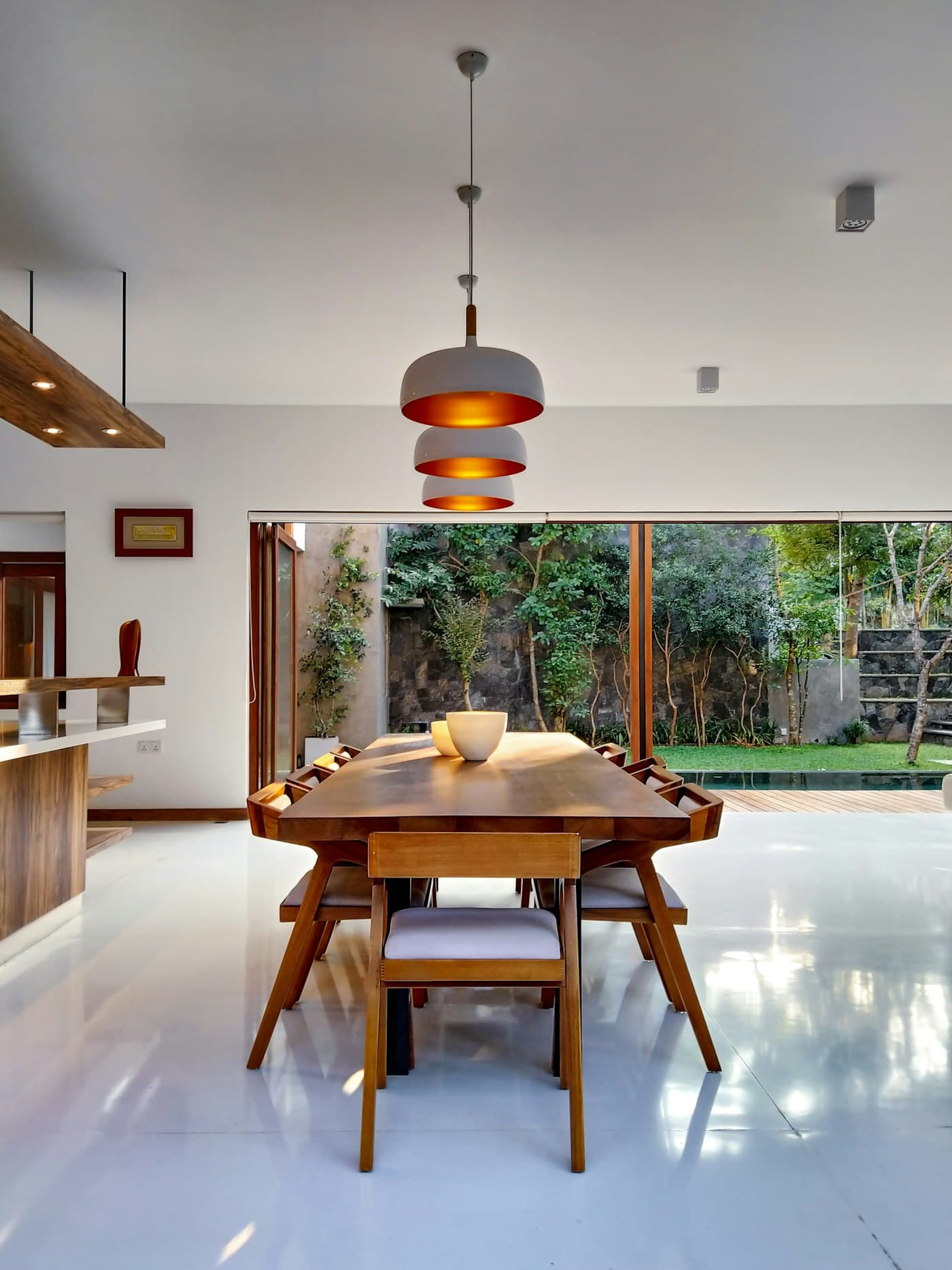 Open dining room with a wooden table under a copper pendant