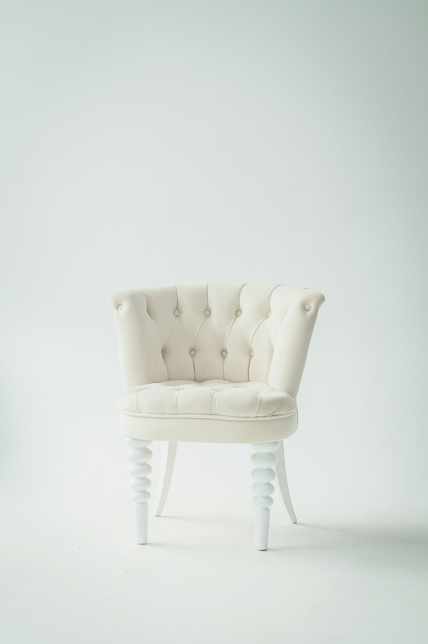 Small tufted ivory velvet chair with turned white legs