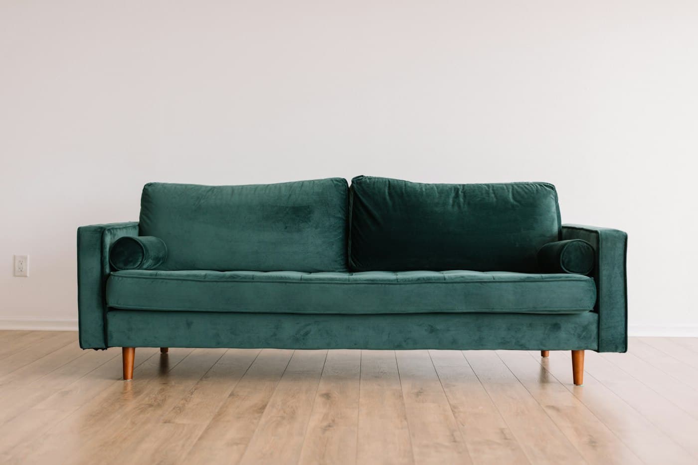Deep green velvet sofa with slim wooden legs