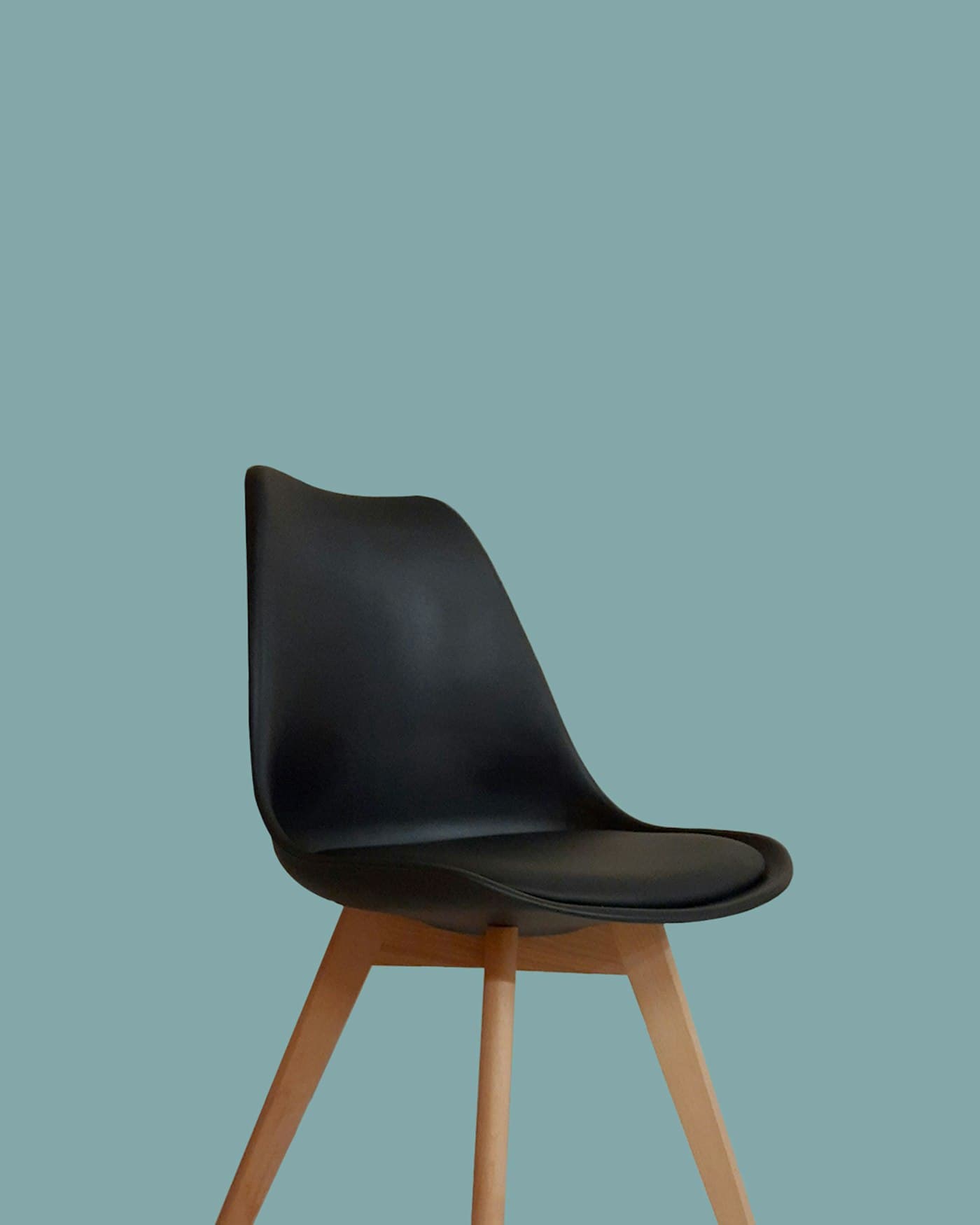 Black moulded side chair with a cushioned seat and splayed oak legs