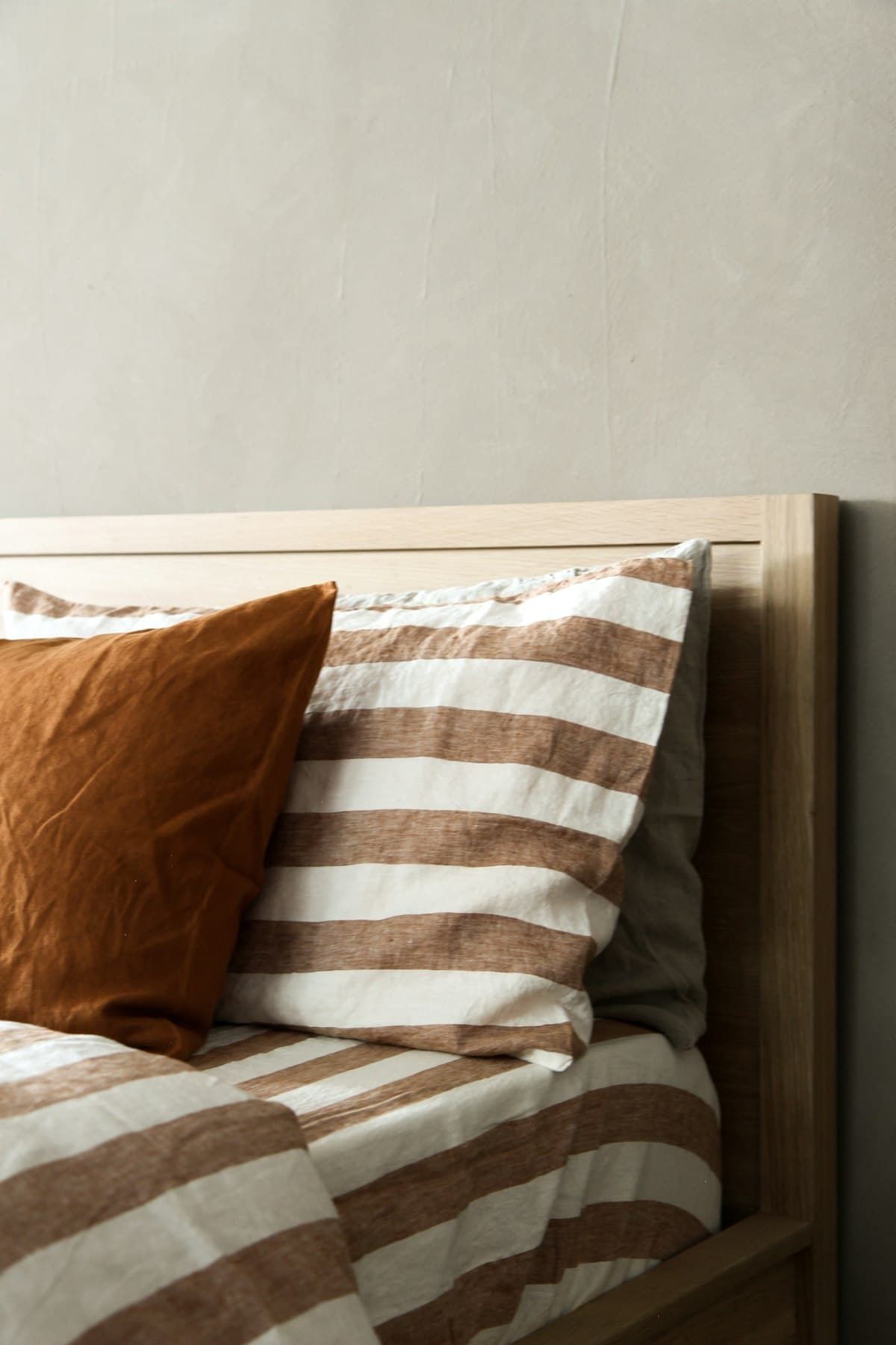 Close-up of striped linen bedding against a wooden headboard