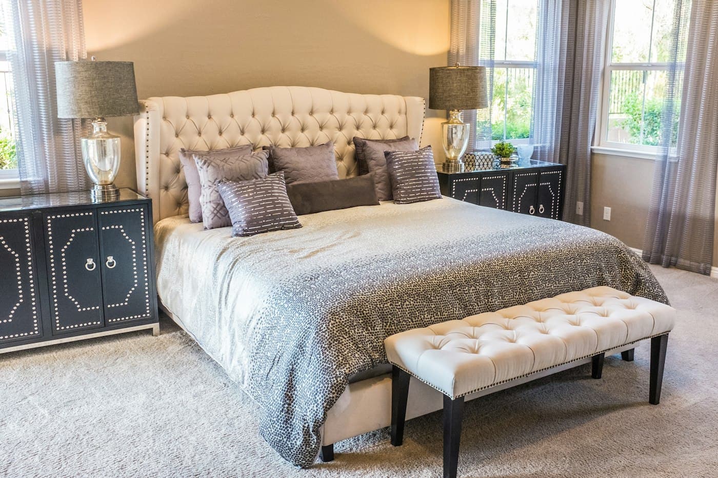 Bed with a tall buttoned ivory headboard and a matching bench at its foot