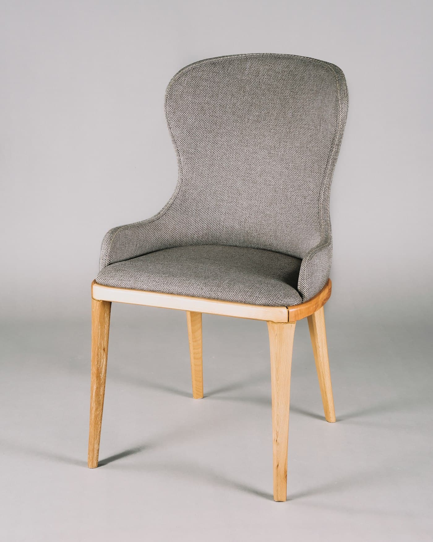 Upholstered grey dining chair with a curved back and light beech legs