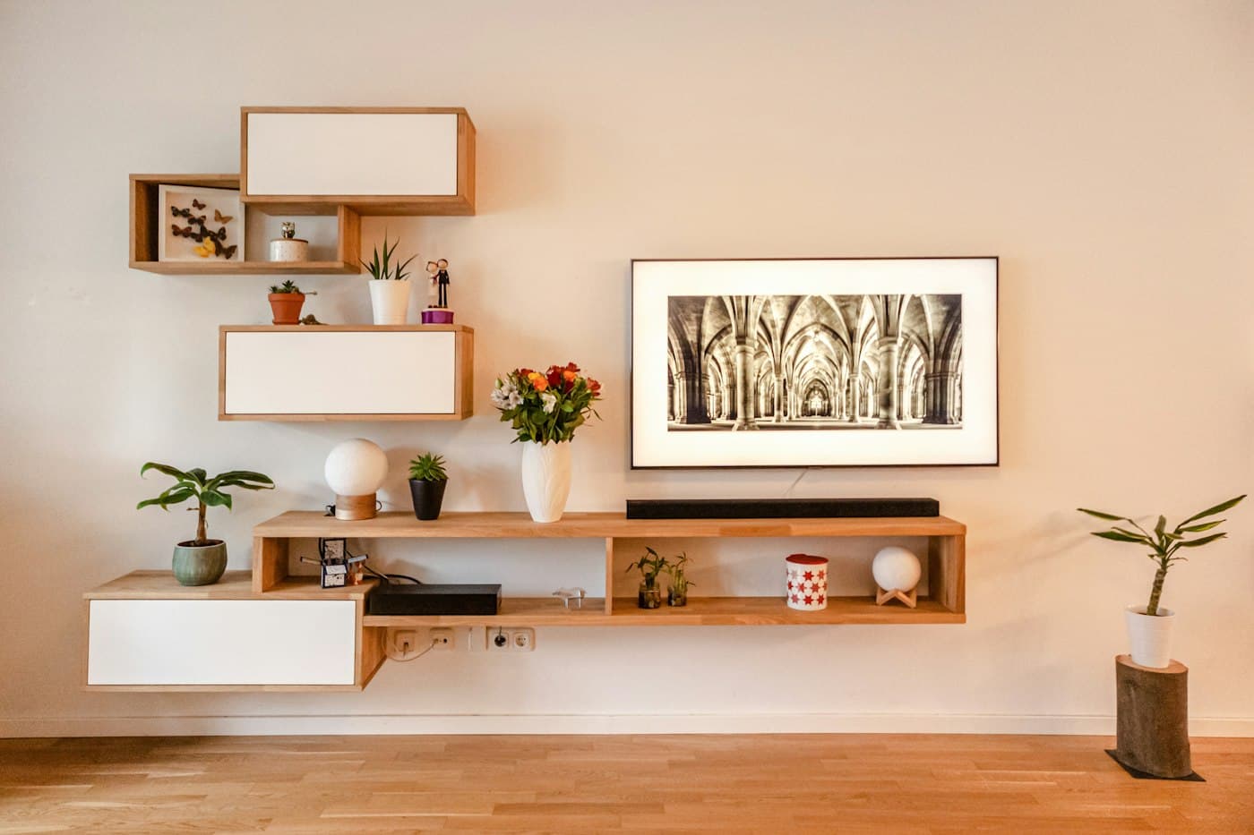 Floating oak wall shelves with books, plants and framed art